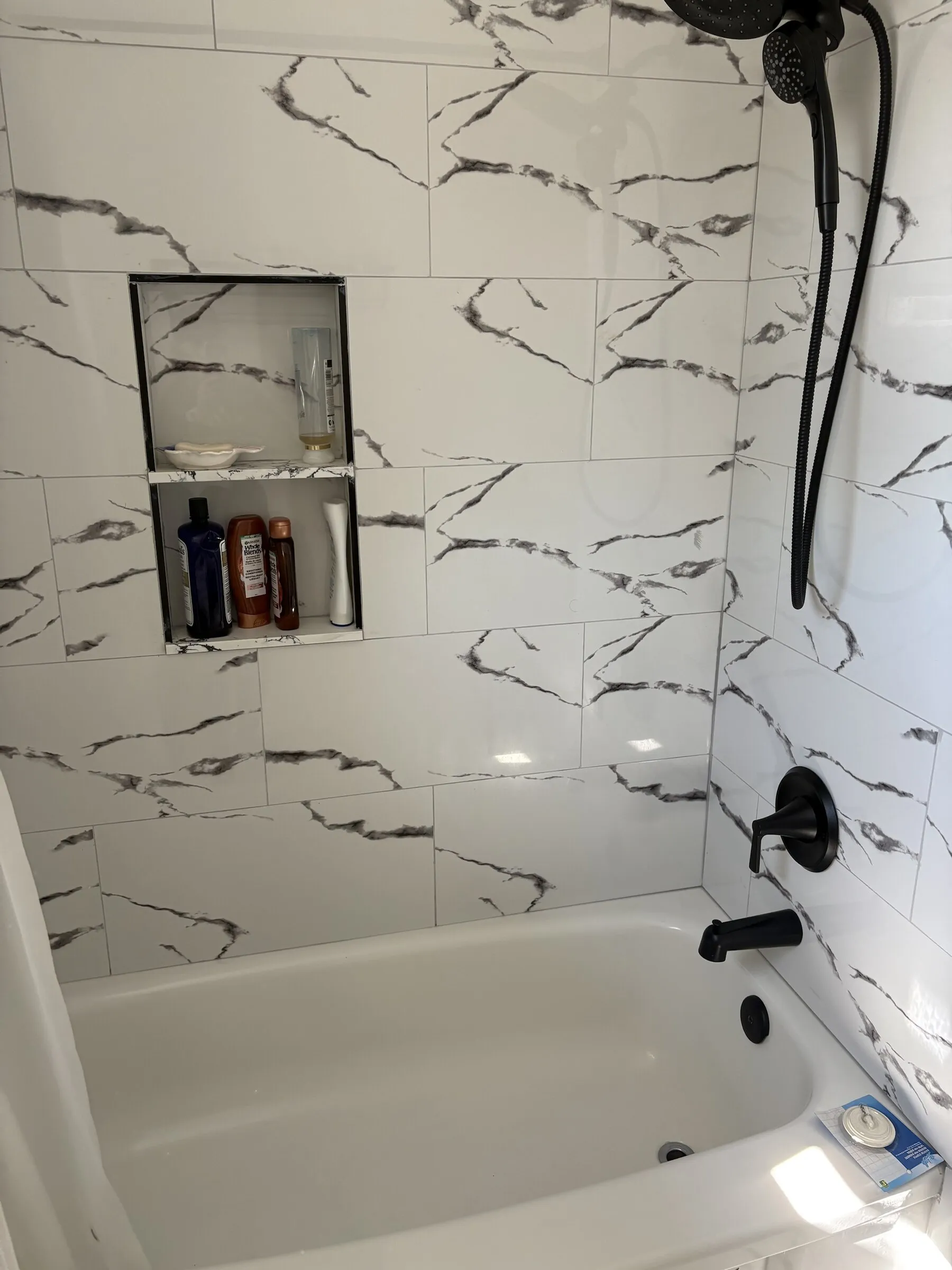 Marble-look tub and shower with matte black fixtures