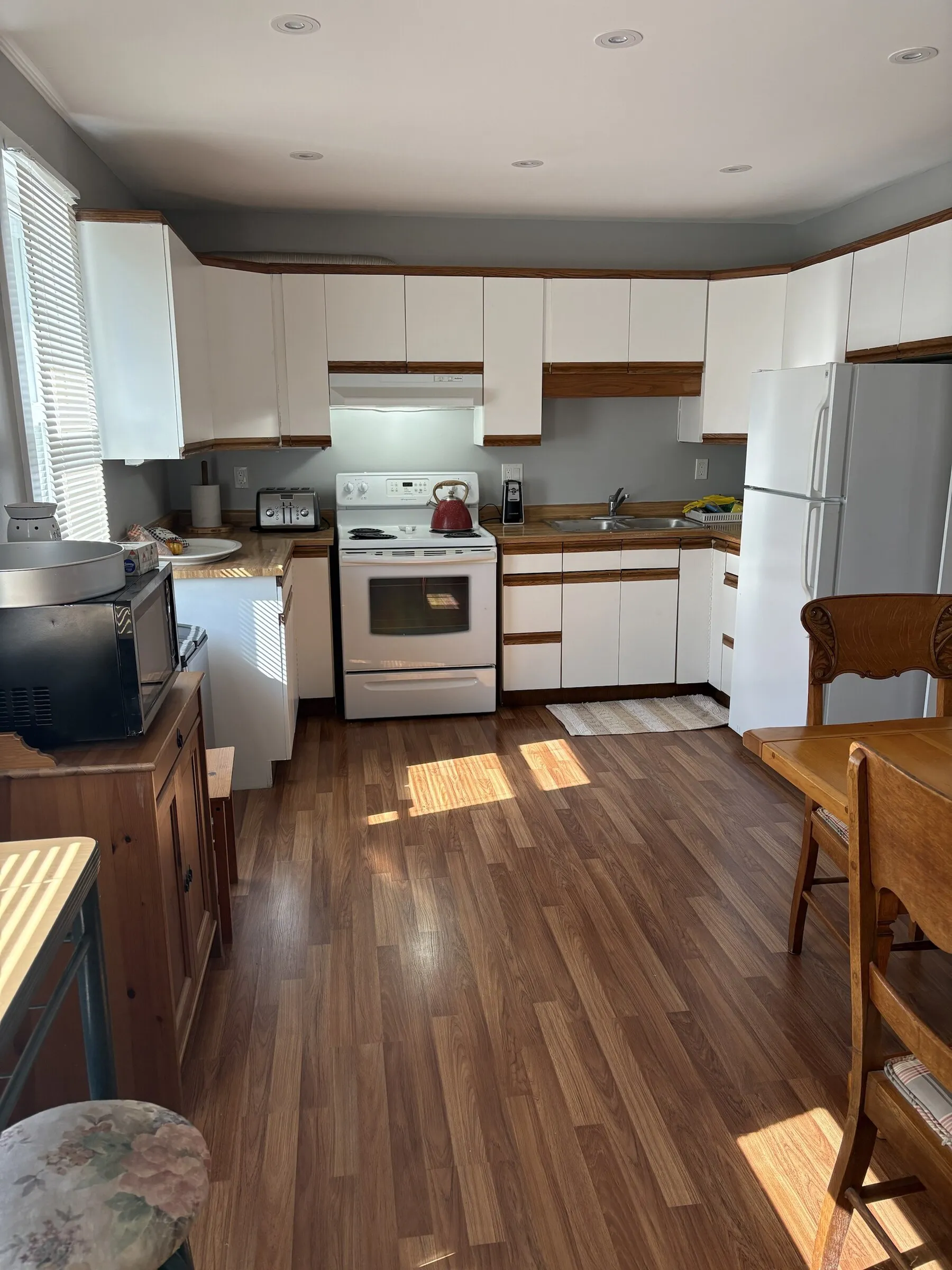 Sunny kitchen with white cabinets and wood floors