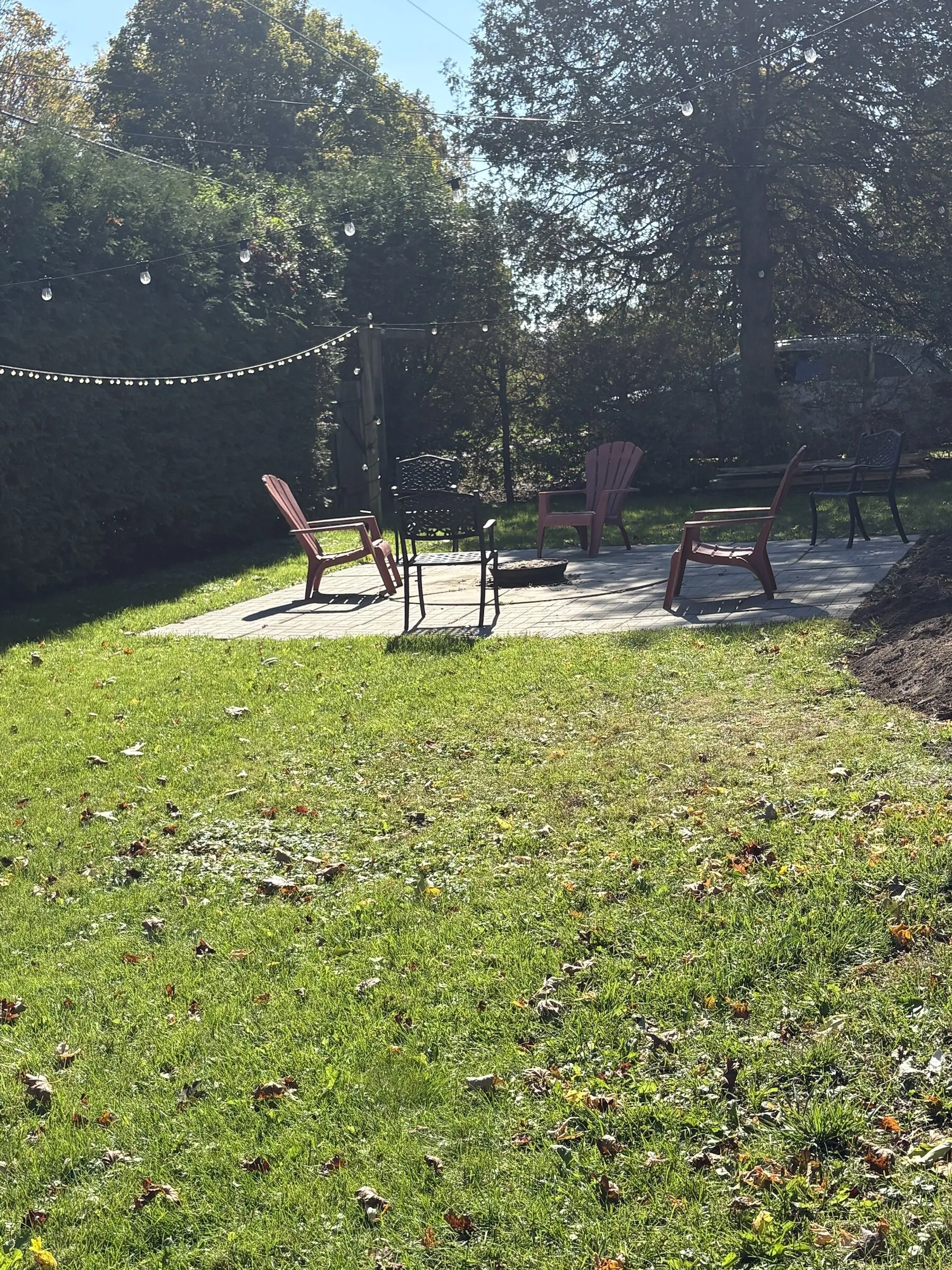 Backyard lawn leading to the fire pit patio under string lights